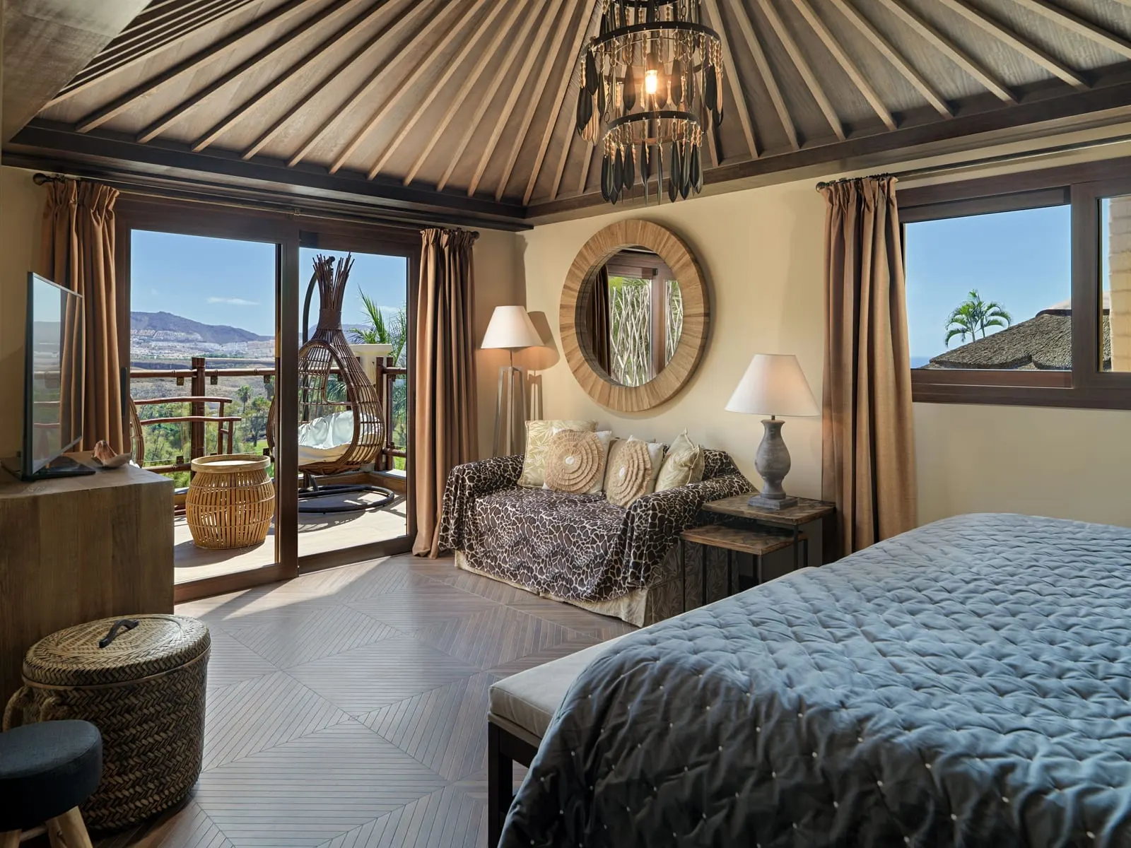 Two-bedroom Lagoon Villa at Royal River: a bedroom with a round mirror and doors to a terrace with a hanging chair