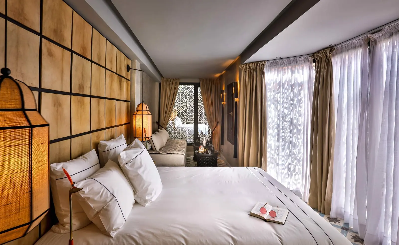 Suite Colonial at Dar Kandi: a white bed beside a long sunlit room with sheer curtains and a sofa at the far end