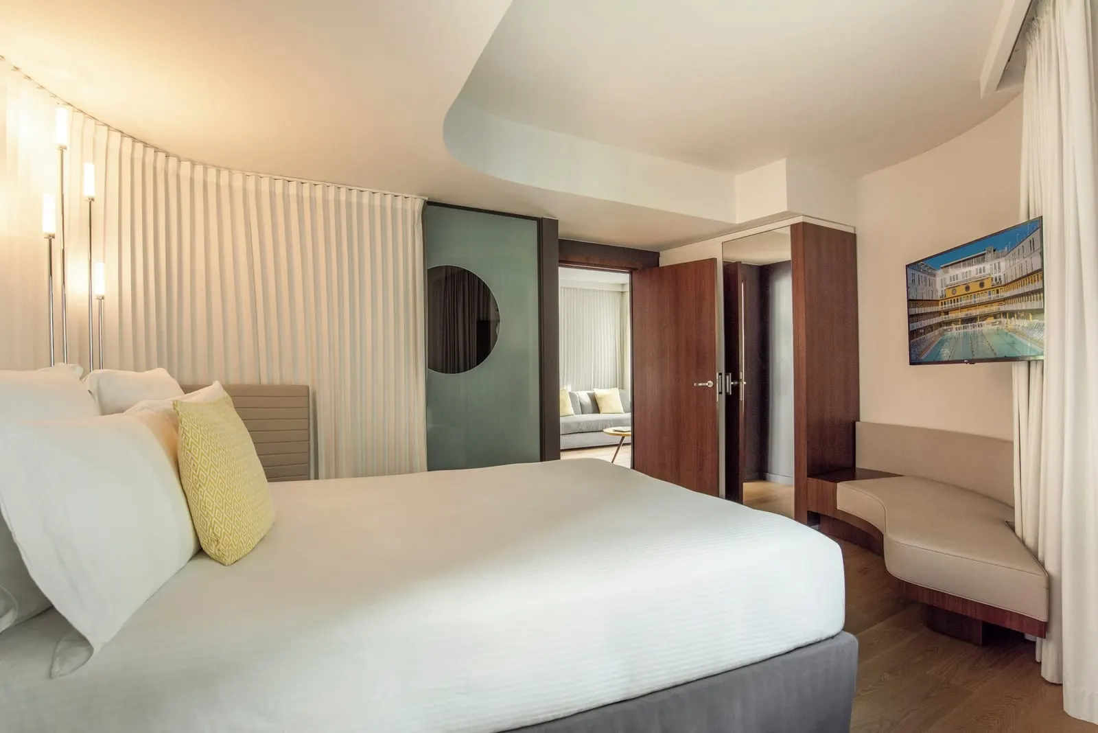 La Grande Suite at Hôtel Molitor Paris: a queen-size bed, a built-in banquette and an open door through to the sitting room