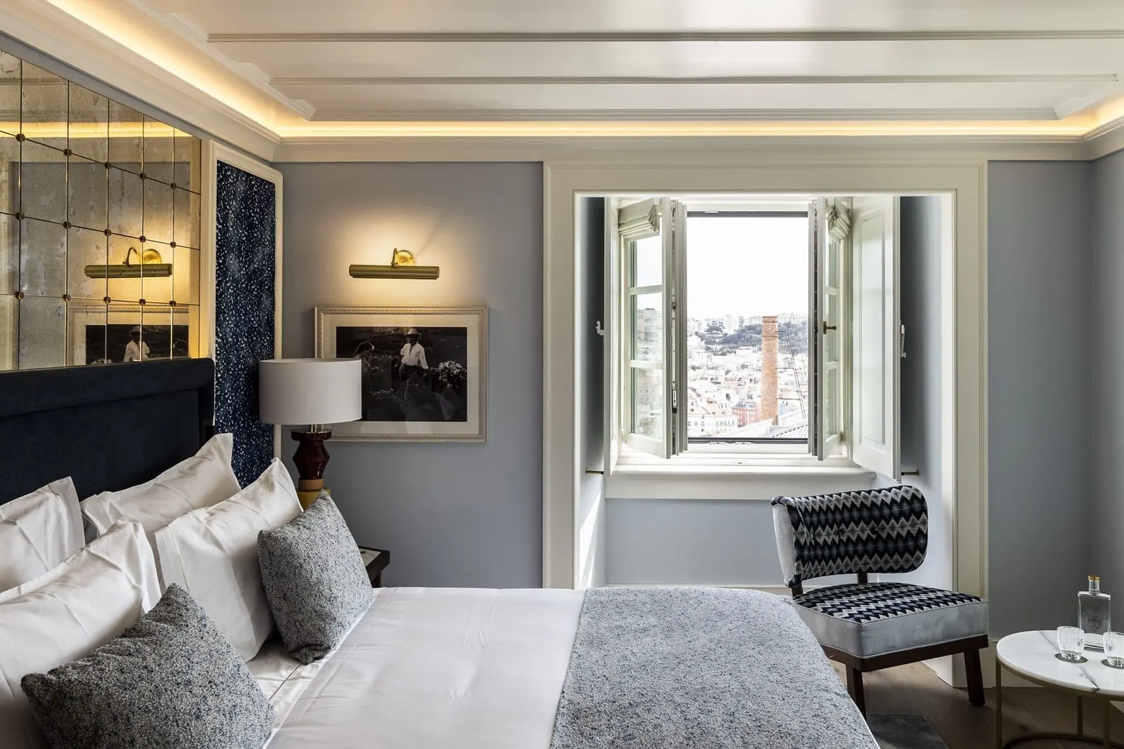 Deluxe Room at Palácio Ludovice: the bed and an open window onto the city rooftops and a tall brick chimney
