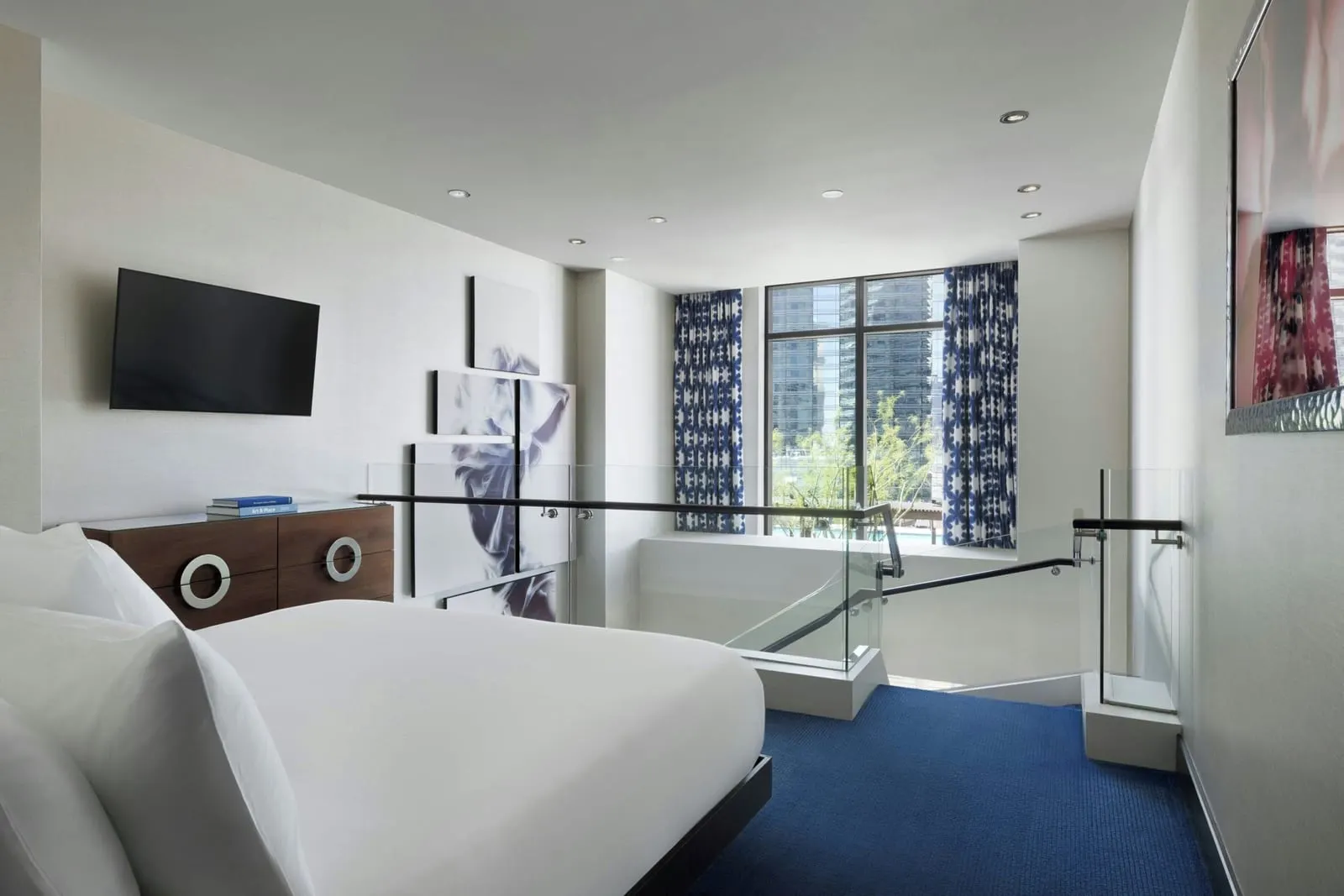 Restore Lanai Suite at The Cosmopolitan of Las Vegas: the loft bedroom, with a bed, a wall-mounted television and a glass balustrade above the staircase