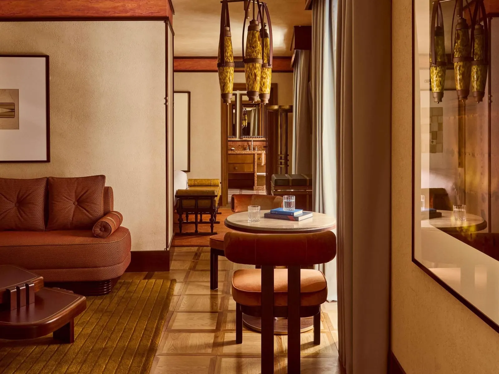 Junior Suite at Orient Express La Minerva: a leather sofa, a round table with a stool and hanging amber lanterns