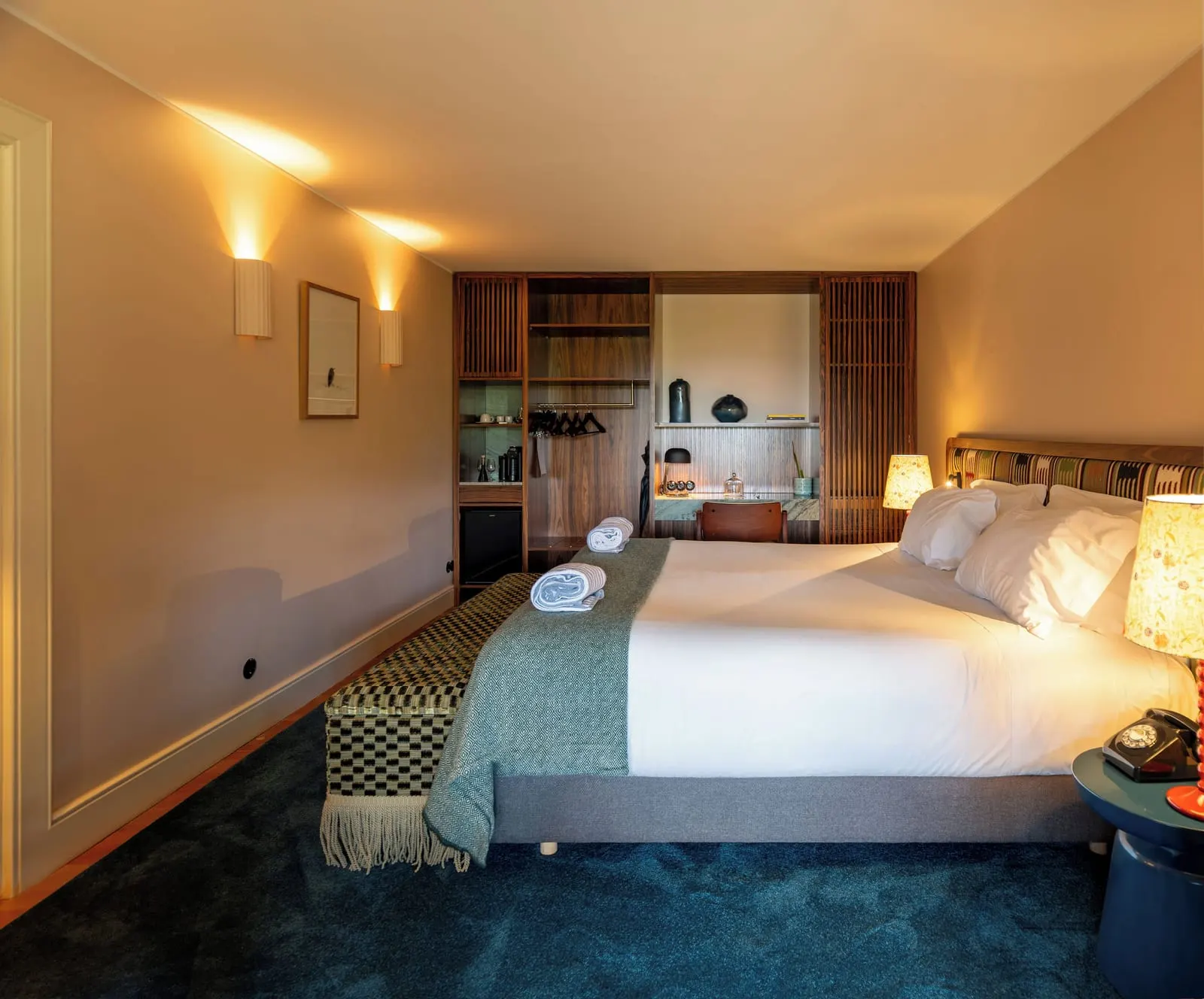 Premium Terrace Accommodation at Quinta Nova: the bed with a green throw, a blue carpet and a wooden wardrobe and desk unit