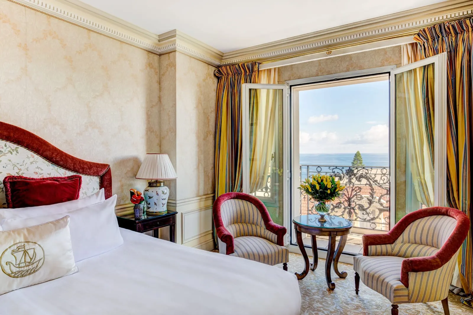 Deluxe Sea View Suite at Hôtel Métropole Monte-Carlo: the bed and two armchairs by French windows open to the sea