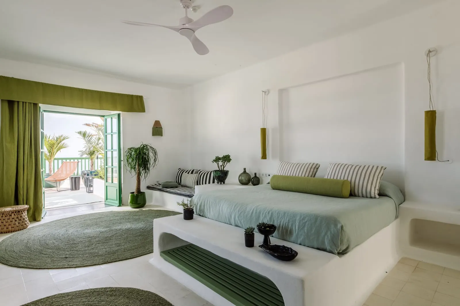 Junior Suite with Terrace and Sea View à l'Hotel César Lanzarote : un lit et un coin salon bas dans une chambre blanche, avec une porte ouverte sur la terrasse