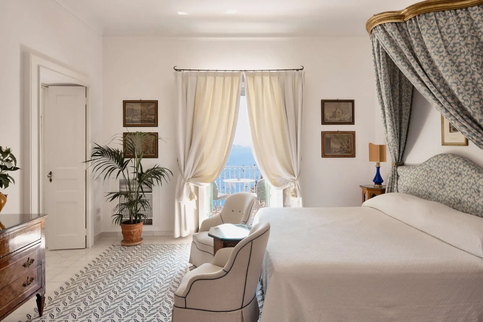 Two Bedroom Suite Sea View at Le Sirenuse: a canopied bed and armchairs beside a curtained window