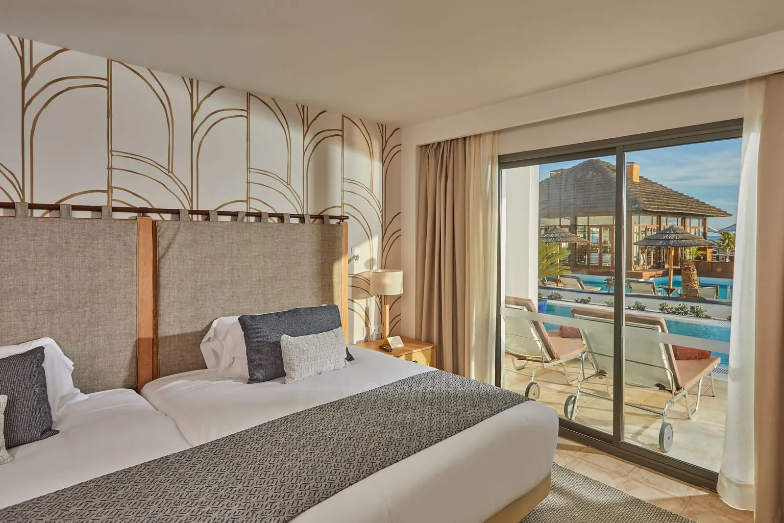 Preferred Club Suite Swim Up al Secrets Lanzarote Resort & Spa: un letto accanto a porte scorrevoli di vetro che si aprono su una terrazza con piscina