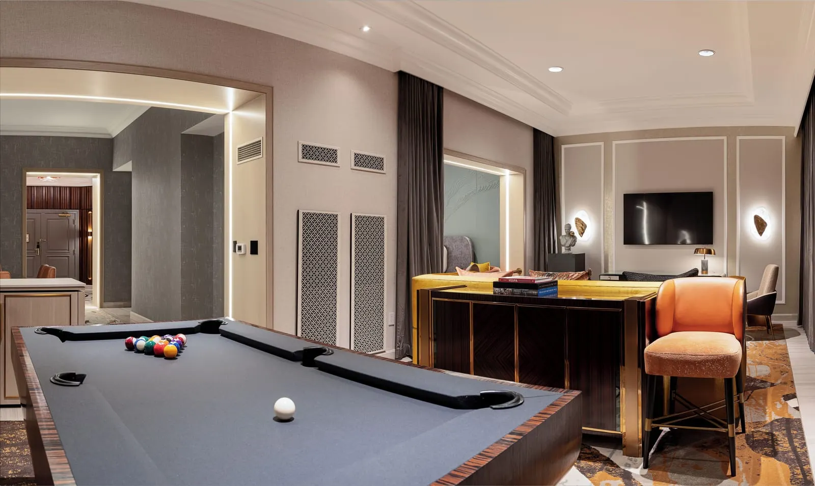 Newly Remodeled Grand King Suite at The Venetian: a pool table in the foreground and, beyond it, a mustard yellow sofa facing a wall-mounted television, with an orange stool at a dark wood console