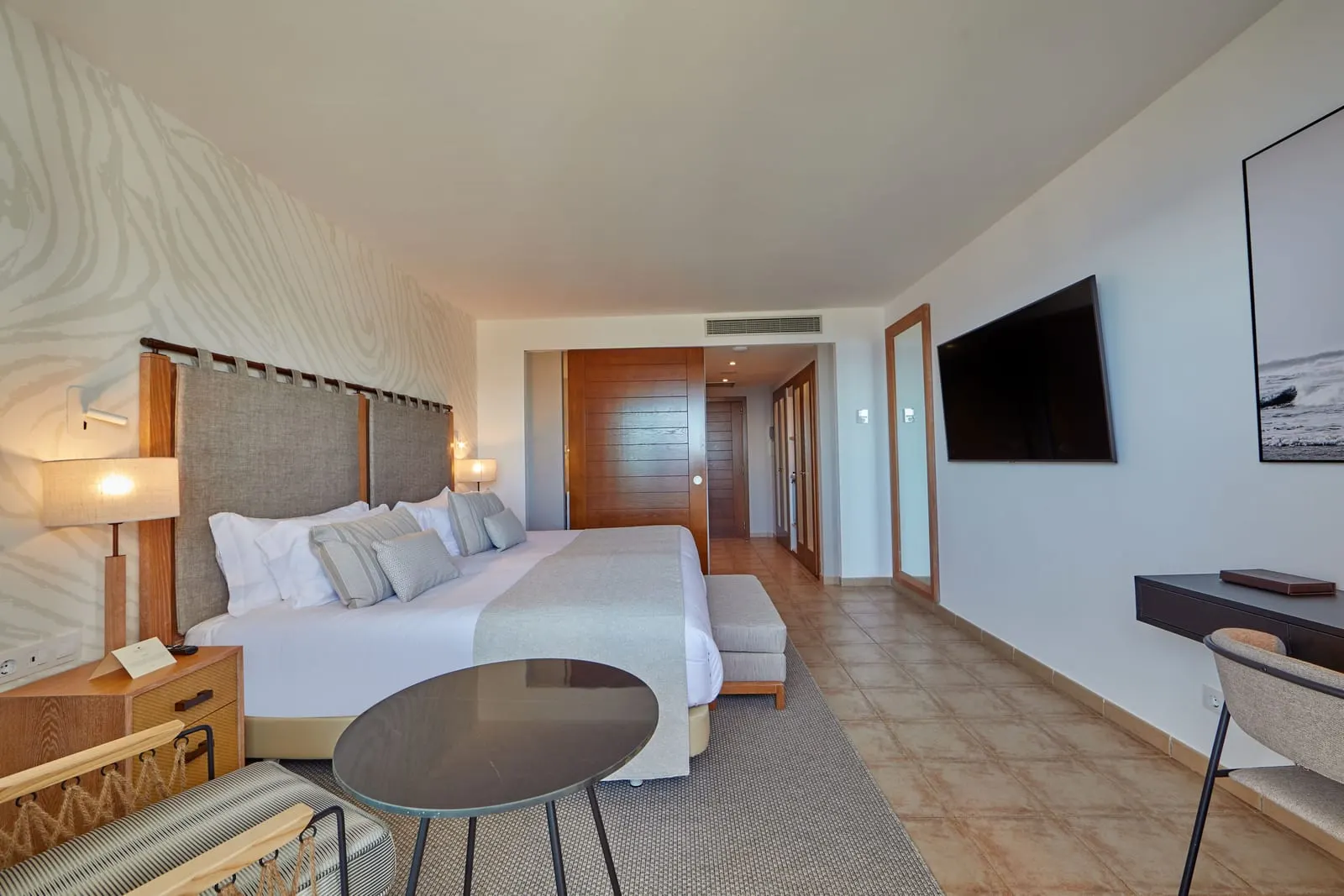 Double Ocean View al Secrets Lanzarote Resort & Spa: un'ampia camera con un grande letto, un tavolo rotondo, un televisore a parete e una scrivania