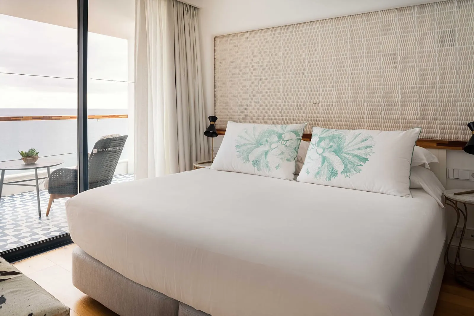 Suite Sea View at Hotel Fariones: a large bed with a woven headboard wall beside a glass door to the terrace and the sea