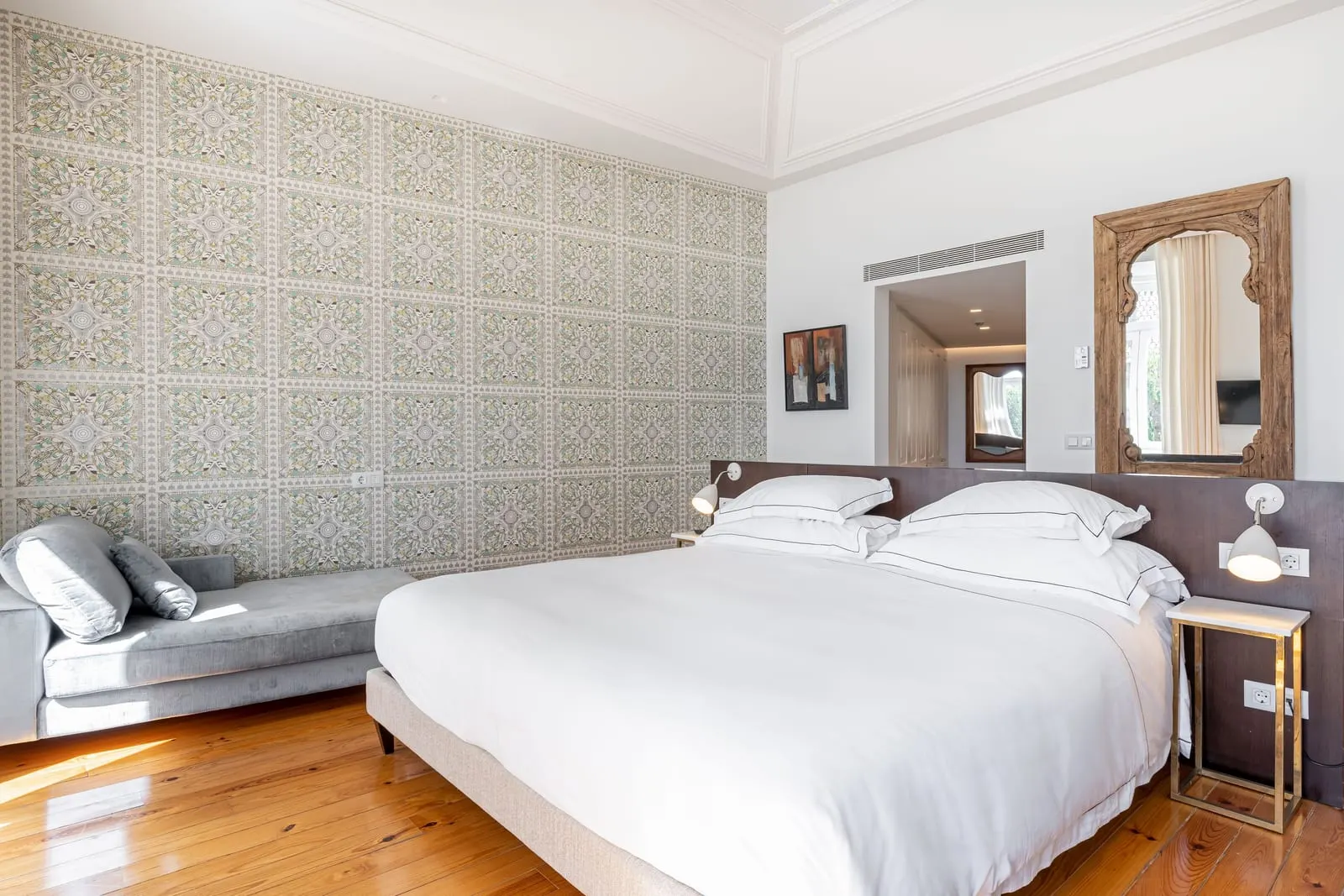 Junior Suite with River View at Santiago de Alfama: the bed, a grey chaise longue, patterned walls and a carved mirror