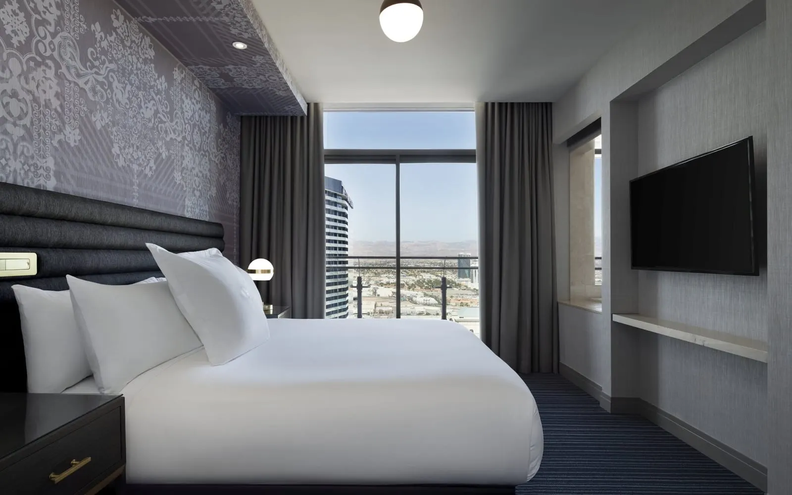 Terrace One Bedroom Suite at The Cosmopolitan of Las Vegas: the bedroom, with a king bed against a patterned wall, a wall-mounted television and a full-height window