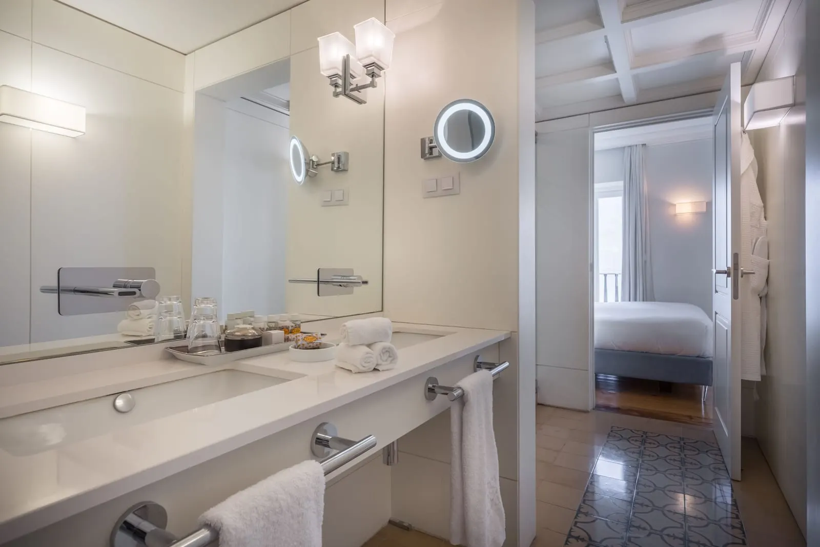 Classic River Bedroom bathroom at Santiago de Alfama: a white basin counter, a lit mirror and the door through to the bedroom