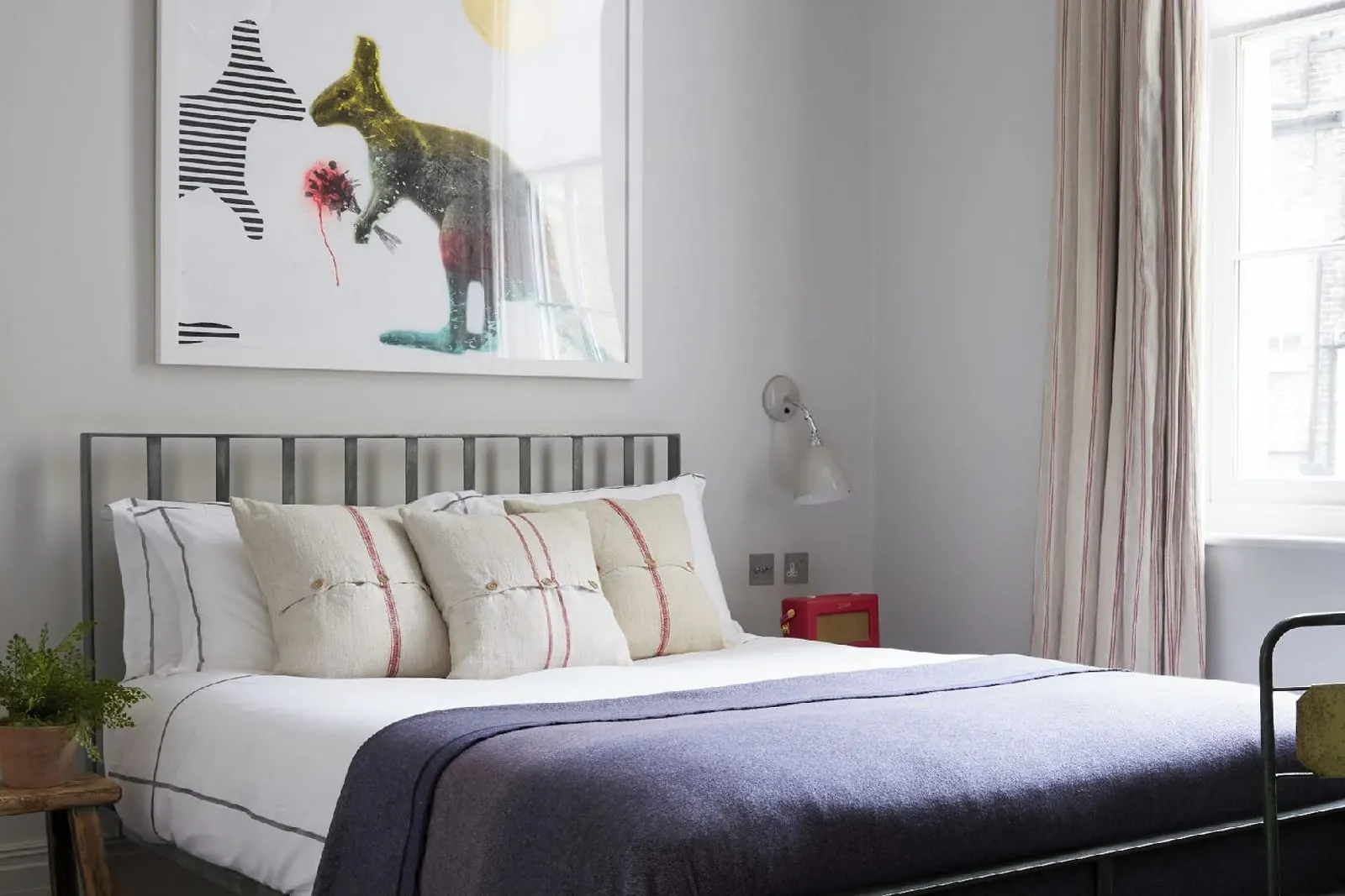 Small Room at Artist Residence London: the bed with a metal frame, a dark throw, a large framed print and a window