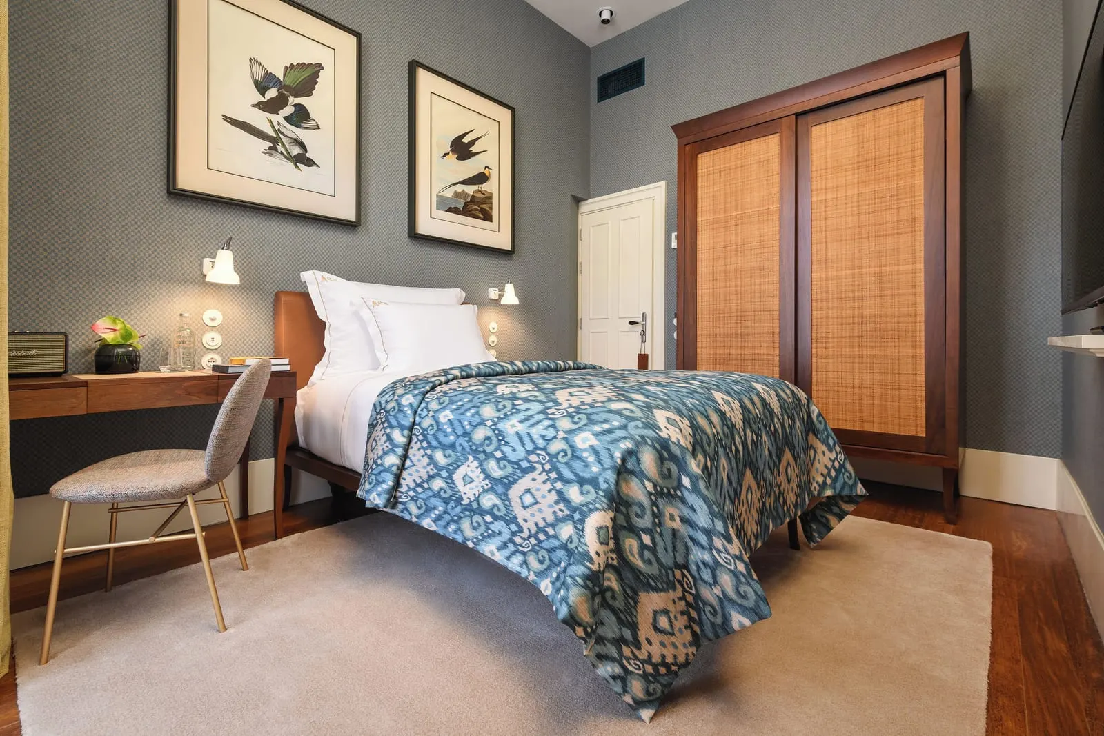 Single room at Bairro Alto Hotel: the bed with a blue throw, a desk and chair, and a wardrobe with woven panels