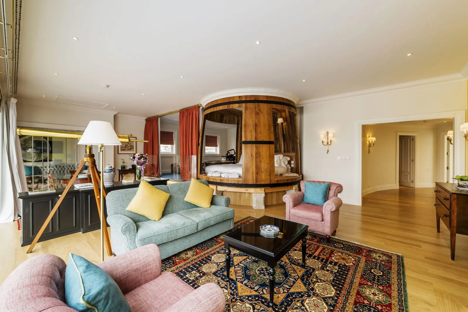 The Presidential Suite at The Yeatman: the lounge with sofas on a rug, and the master bed inside a giant barrel beyond