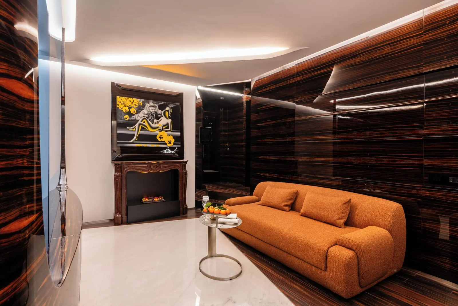 Premier Suite at ROMEO Roma: an orange sofa and a side table facing a fireplace, between ebony-panelled walls