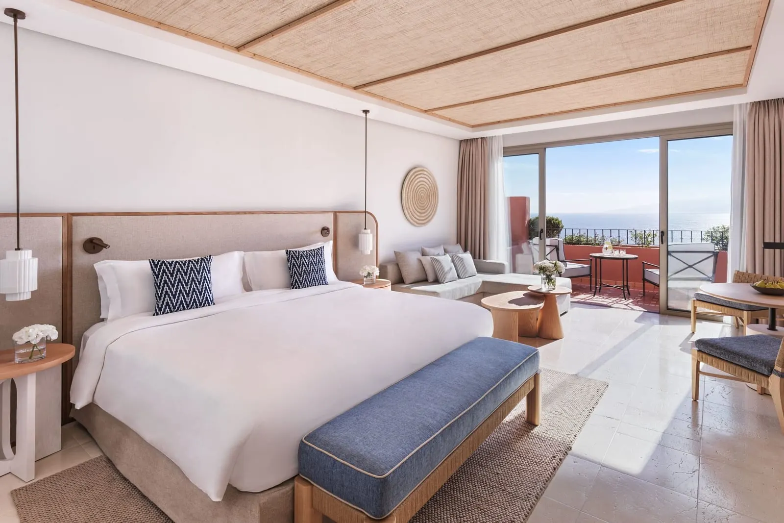 Deluxe Room, Ocean View at the Ritz-Carlton Abama: a king bed, a blue bench and balcony doors with the sea beyond