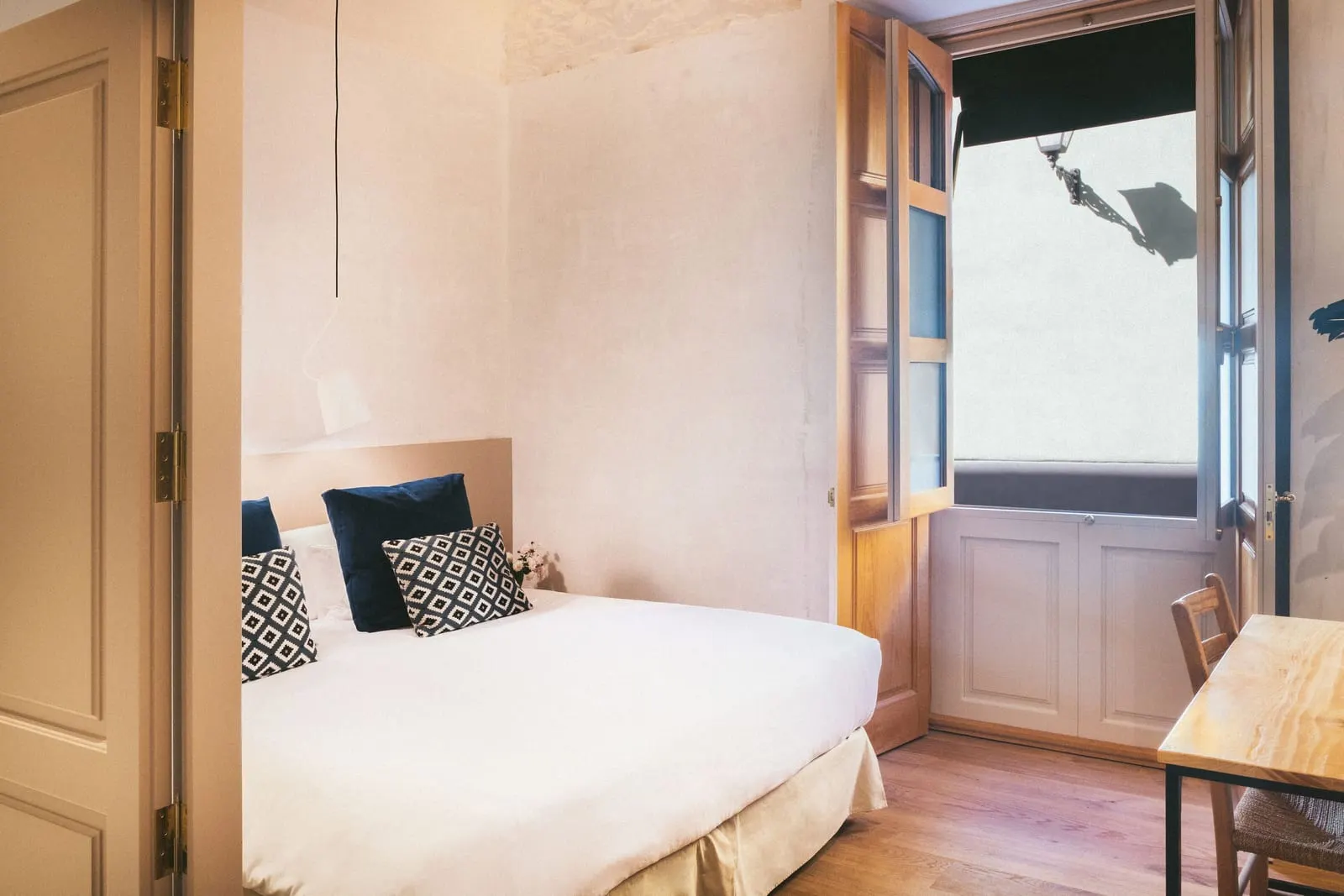 Classic Exterior at Hotel Veintiuno: a double bed beside a tall glazed door with its wooden shutters folded open under an awning, and a wooden desk and chair
