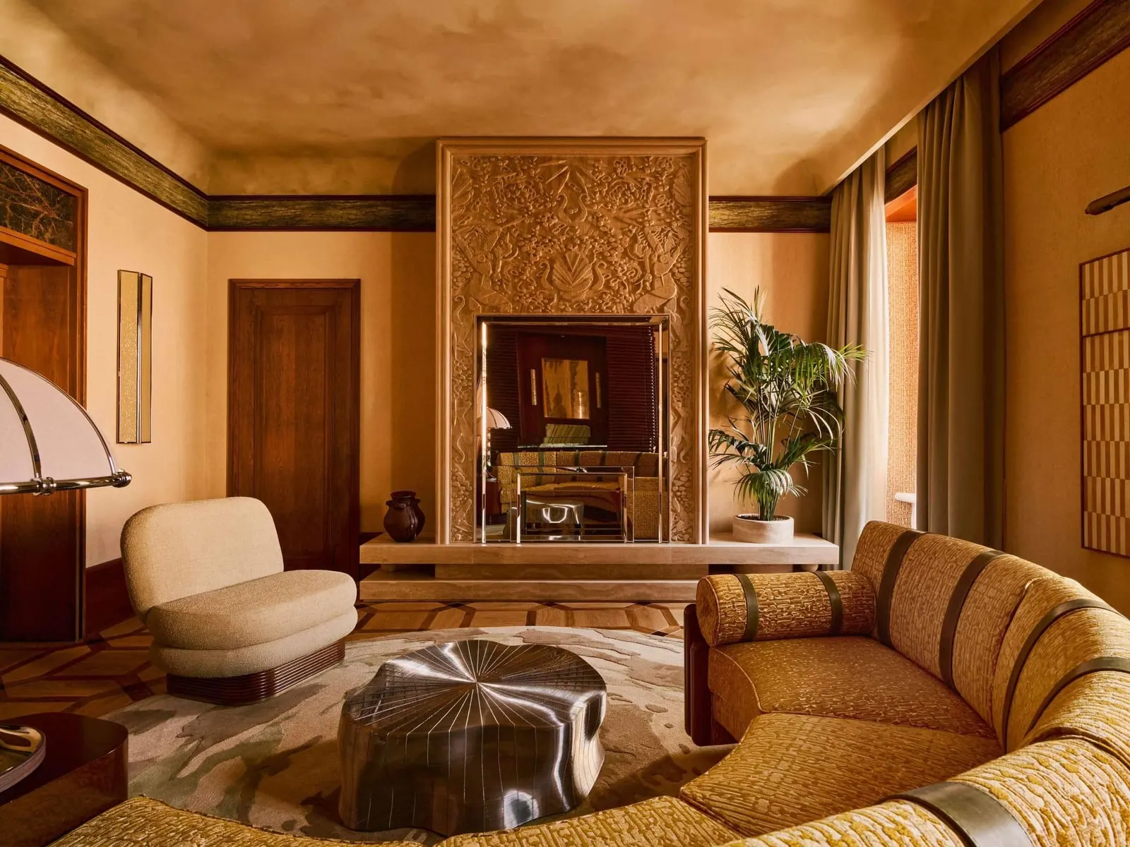 Obelisco Suite at Orient Express La Minerva: the living room with a carved fireplace, a curved sofa and a cream armchair