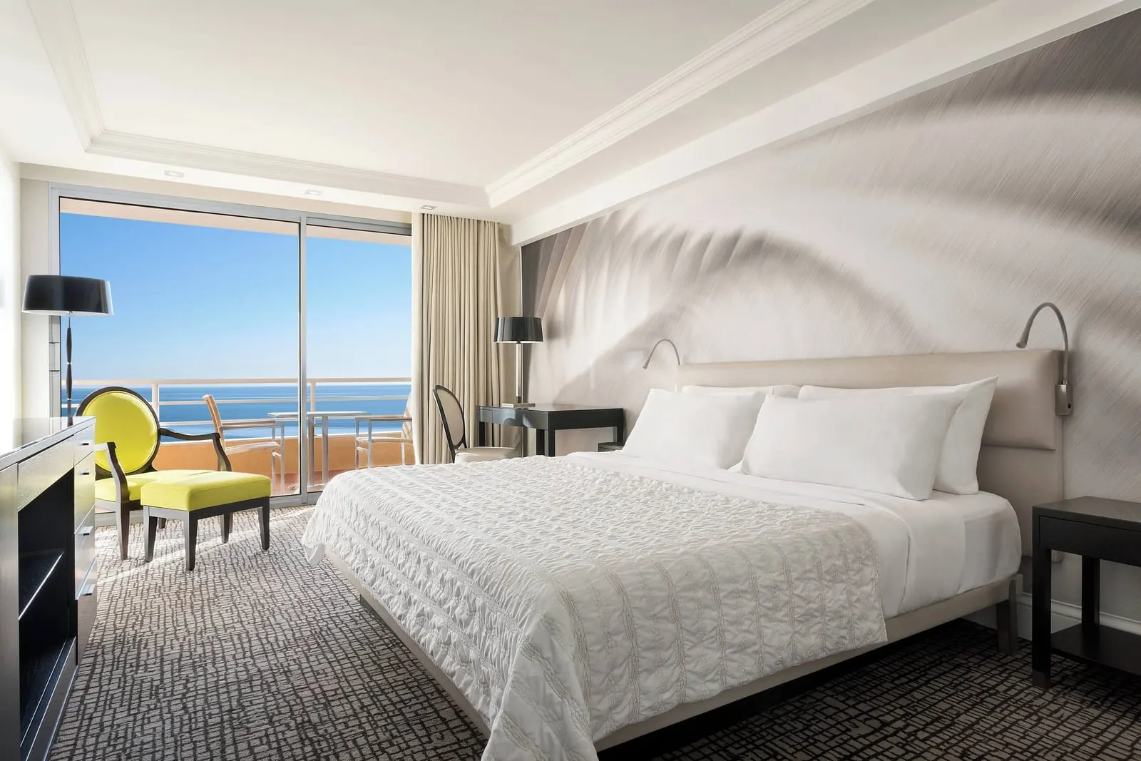 Deluxe sea-view room with balcony at Le Méridien Beach Plaza: the bed, a yellow armchair and glass doors to the sea