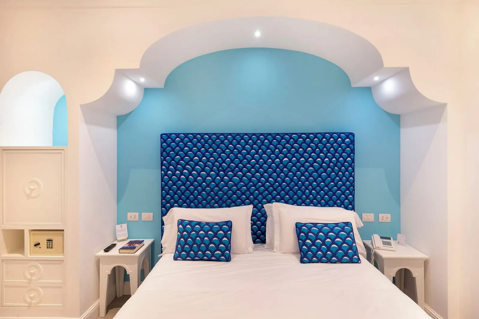Superior Large Room with partial sea view balcony all'Hotel Tramonto d'Oro: un letto matrimoniale con testiera blu a motivi in un'alcova turchese, tra due comodini bianchi.