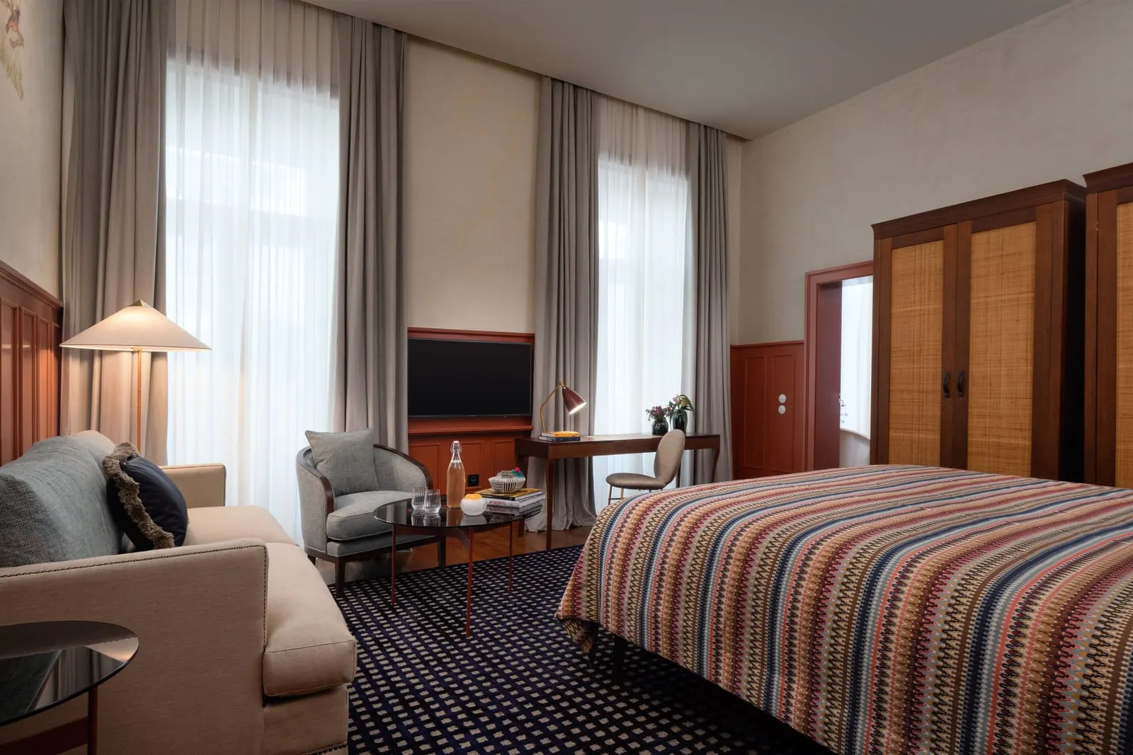 Prestige Chiado room at Bairro Alto Hotel: a sofa and armchair by two tall windows, a desk and the bed