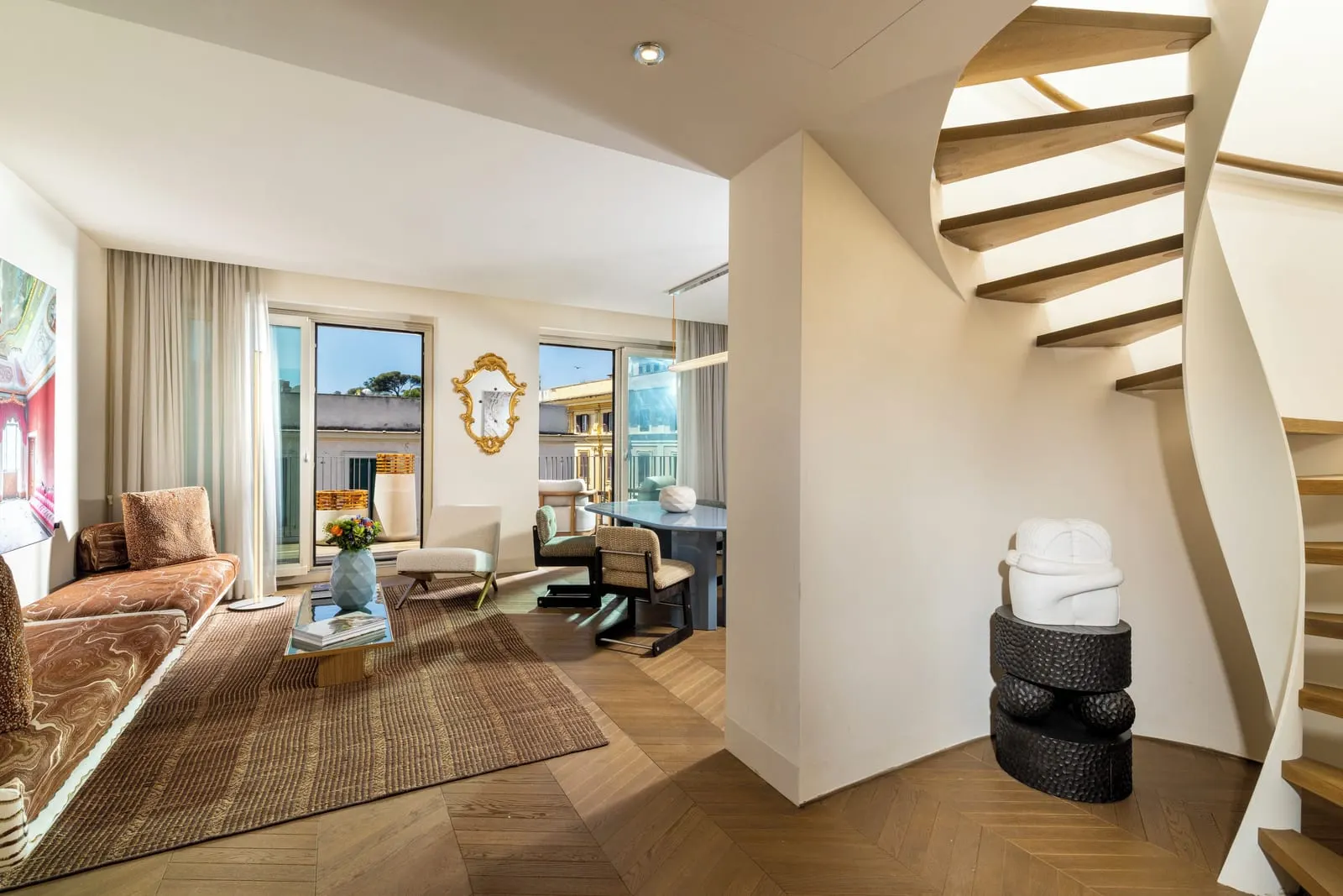 Lateran Gallery Suite at Palazzo Manfredi: the living room, a dining table and the spiral stair to the upper floor