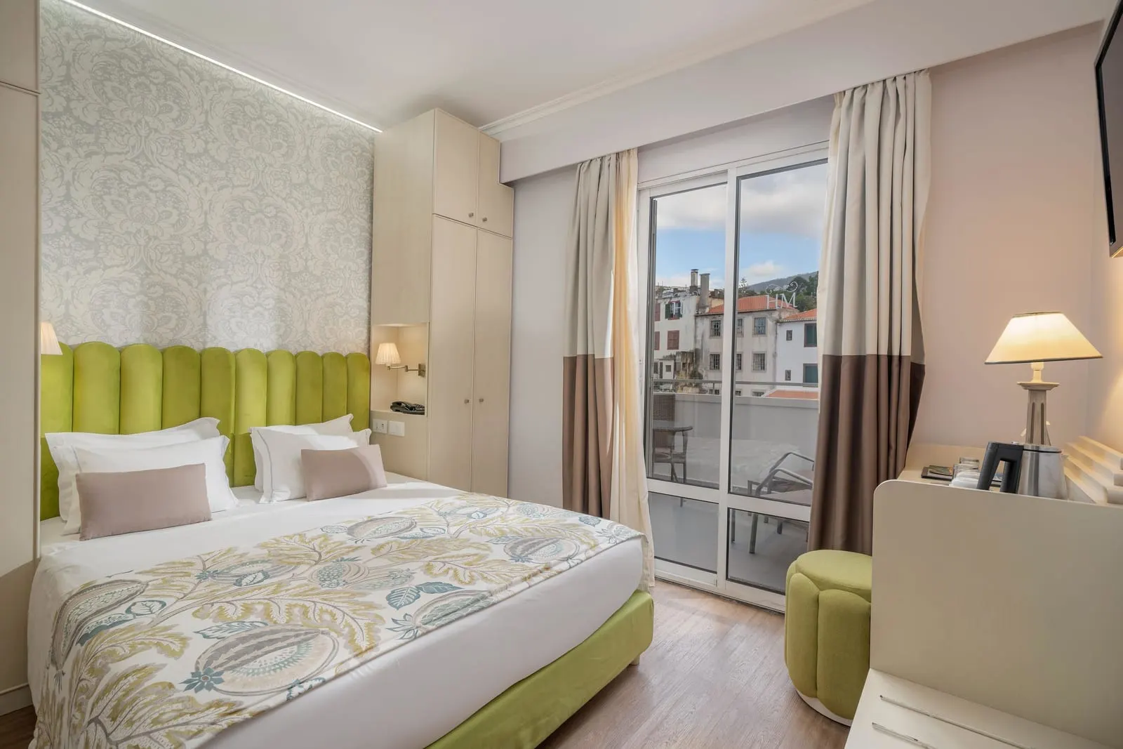 Superior Connecting Room im Hotel Madeira: ein Doppelbett unter einem grünen gepolsterten Kopfteil, mit einer Glastür zu einem Balkon