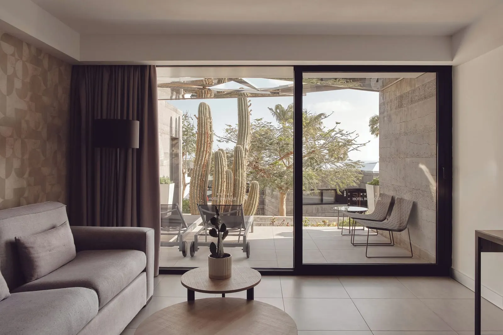Classic Suite at La Isla y el Mar Hotel Boutique: a sitting area with a sofa and armchair, opening through sliding glass doors onto a terrace with cacti