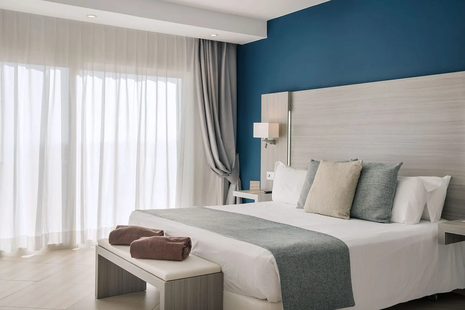 Double Standard at Royal Palm Resort & Spa: a double bed against a dark blue wall with a padded headboard, reading lights and long curtains