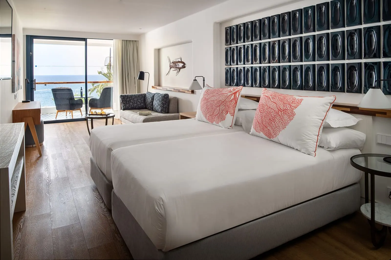 Junior Suite Sea View at Hotel Fariones: twin beds pushed together under a dark tiled wall, with a seating area by the terrace door