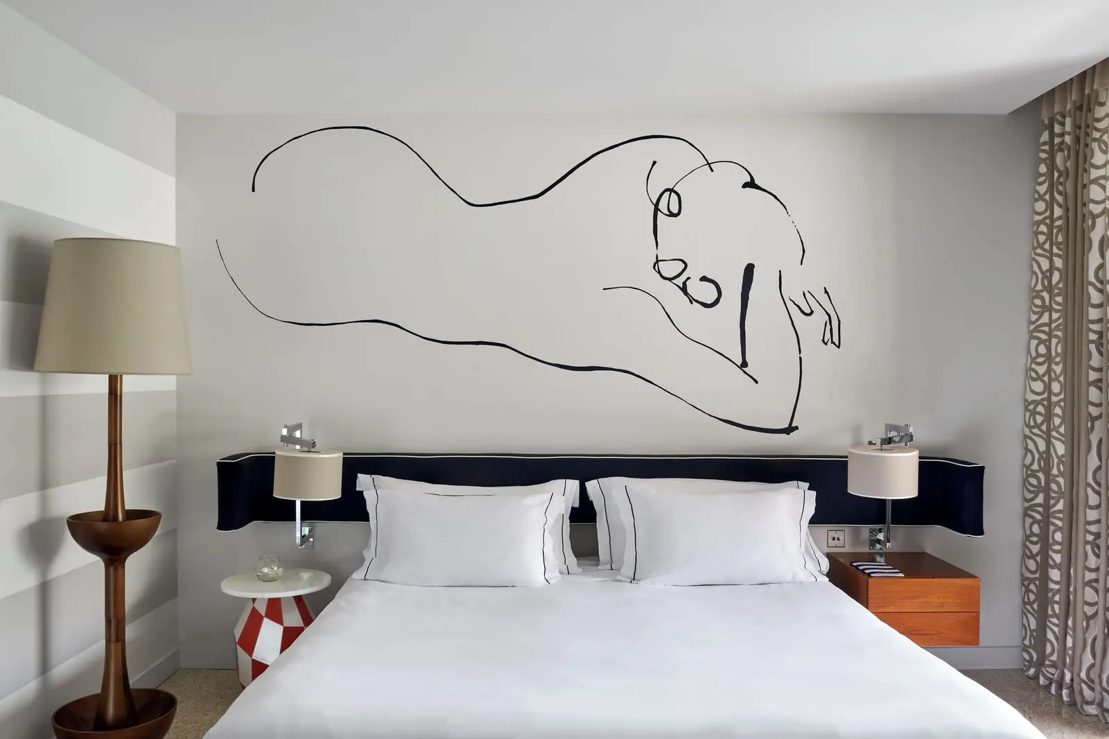 Junior Suite at Monte-Carlo Beach: the bed below a line-drawn mural, with a tall wooden floor lamp