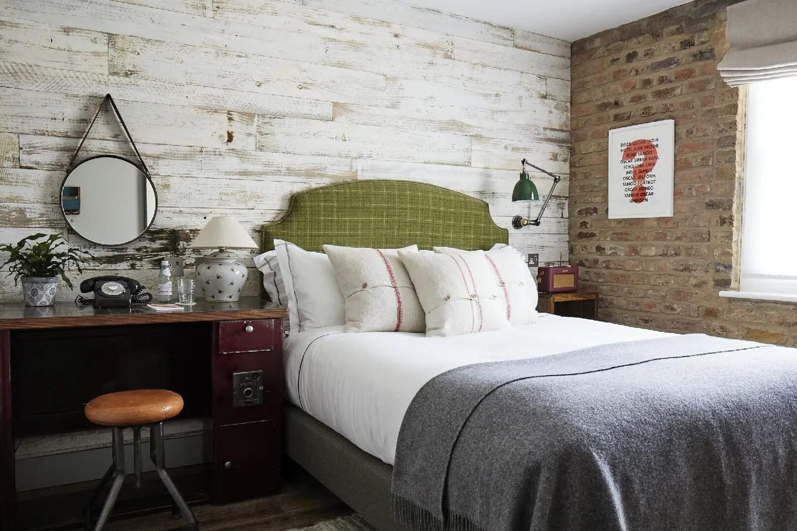 Small Plus Room at Artist Residence London: the bed with a green check headboard, a whitewashed plank wall and a desk