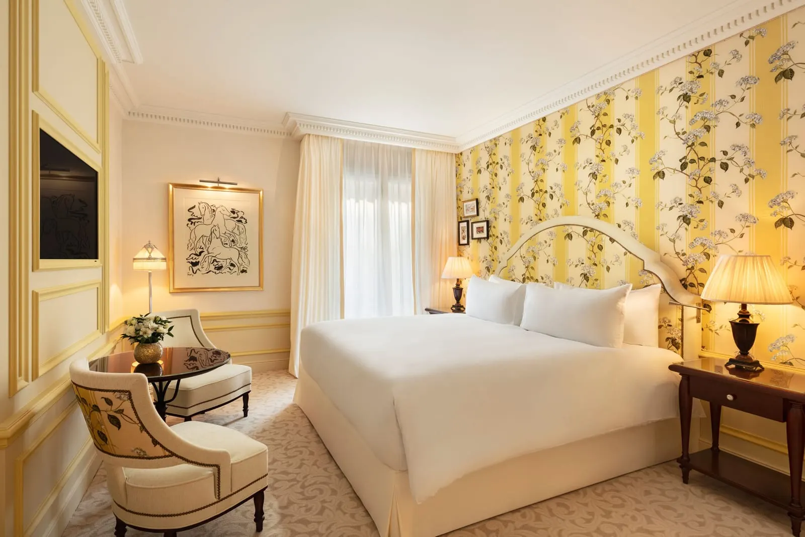 Prestige Room at Hôtel Métropole Monte-Carlo in yellow: the bed against floral wallpaper, an armchair and a round table