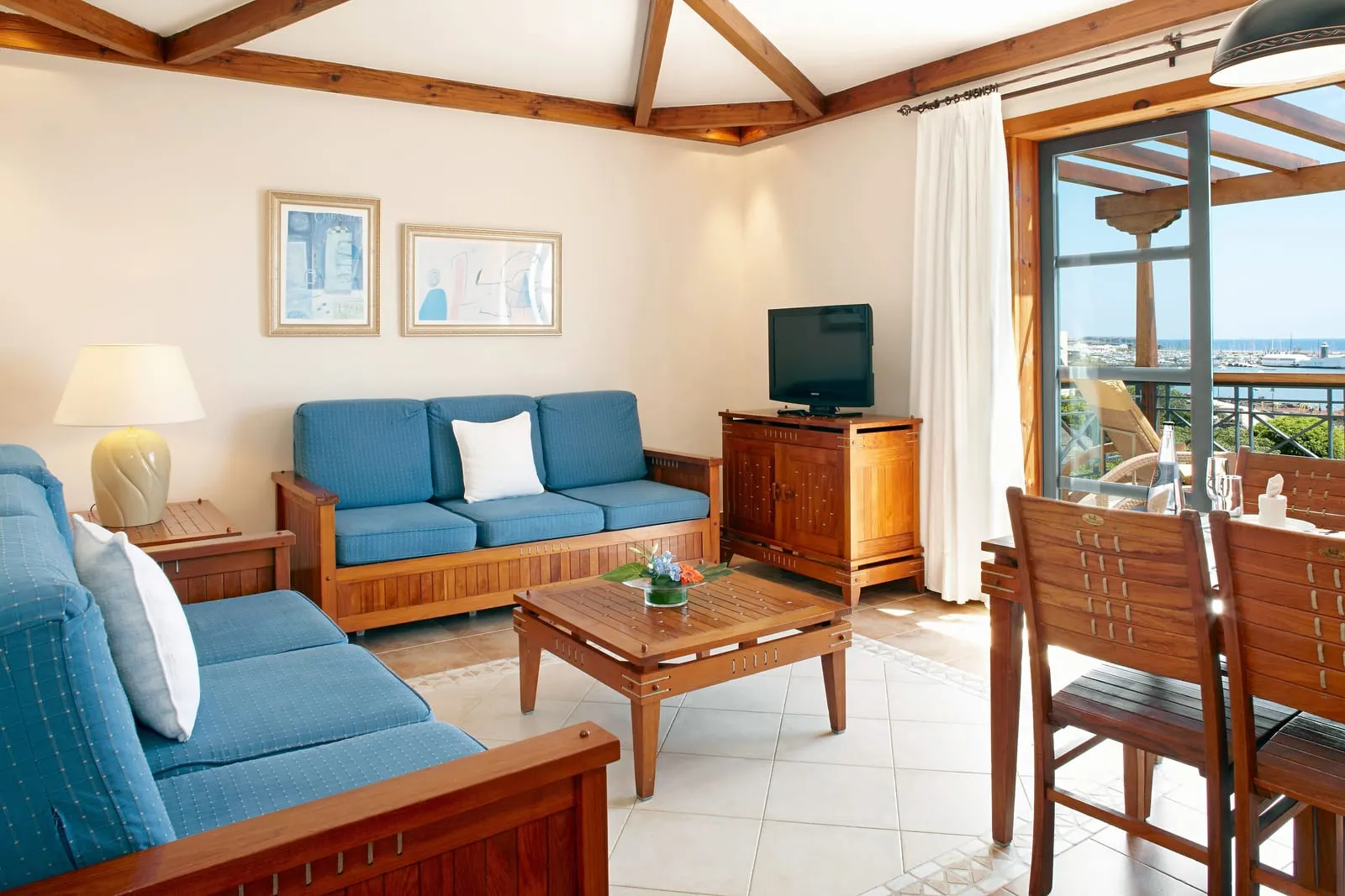 Suite Sea View at Princesa Yaiza Suite Hotel Resort: a living room with blue sofas, a television and a dining table beside a terrace door