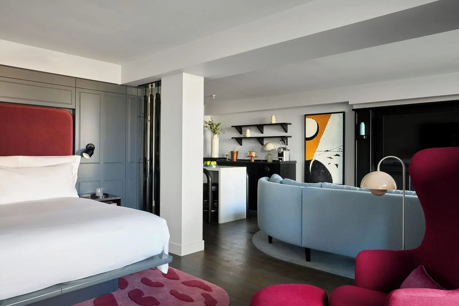 Riverview Balcony Suite at Sea Containers London: the bed, a red wing chair, a blue sofa and a bar with shelves