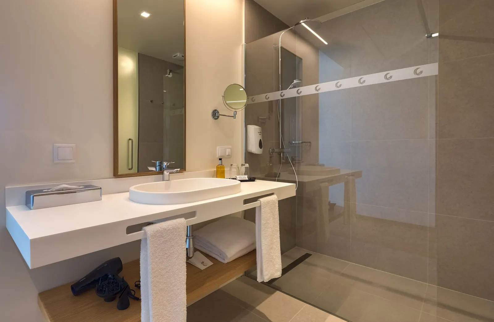 Double Room Sea View Balcony at Sentido Galomar: a bathroom with a white basin counter, a wall mirror, a make-up mirror and a walk-in glass shower