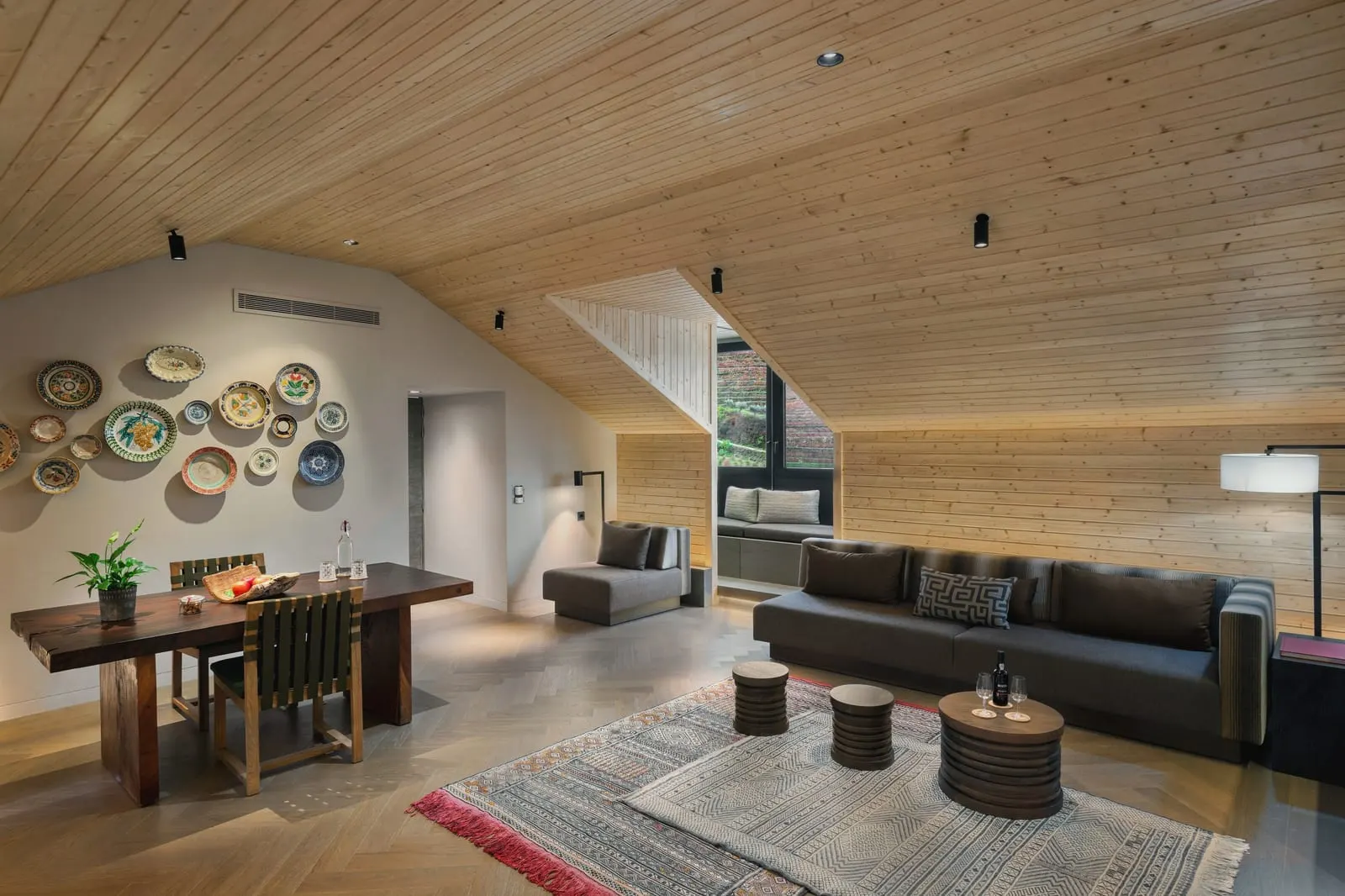 Vineyard Rooftop Suite at Six Senses Douro Valley: a dining table and a sofa under a sloping wooden ceiling