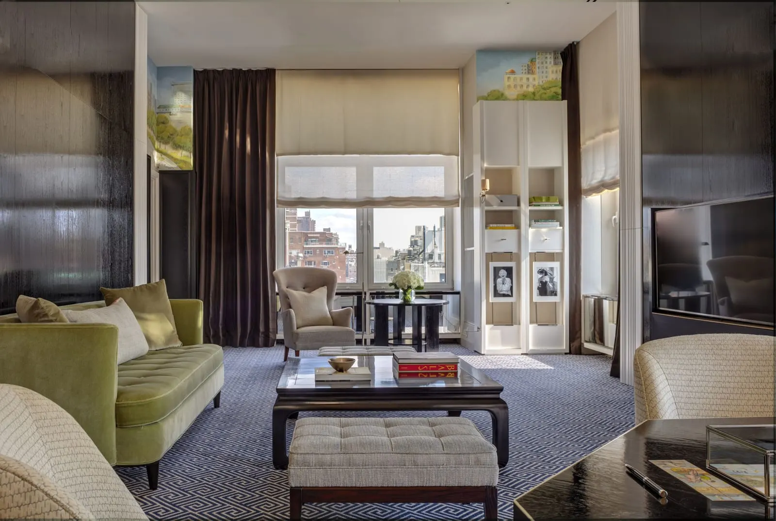 Upper East Side Suite at The Carlyle: a living room with a green velvet sofa, a low table and armchairs facing tall windows