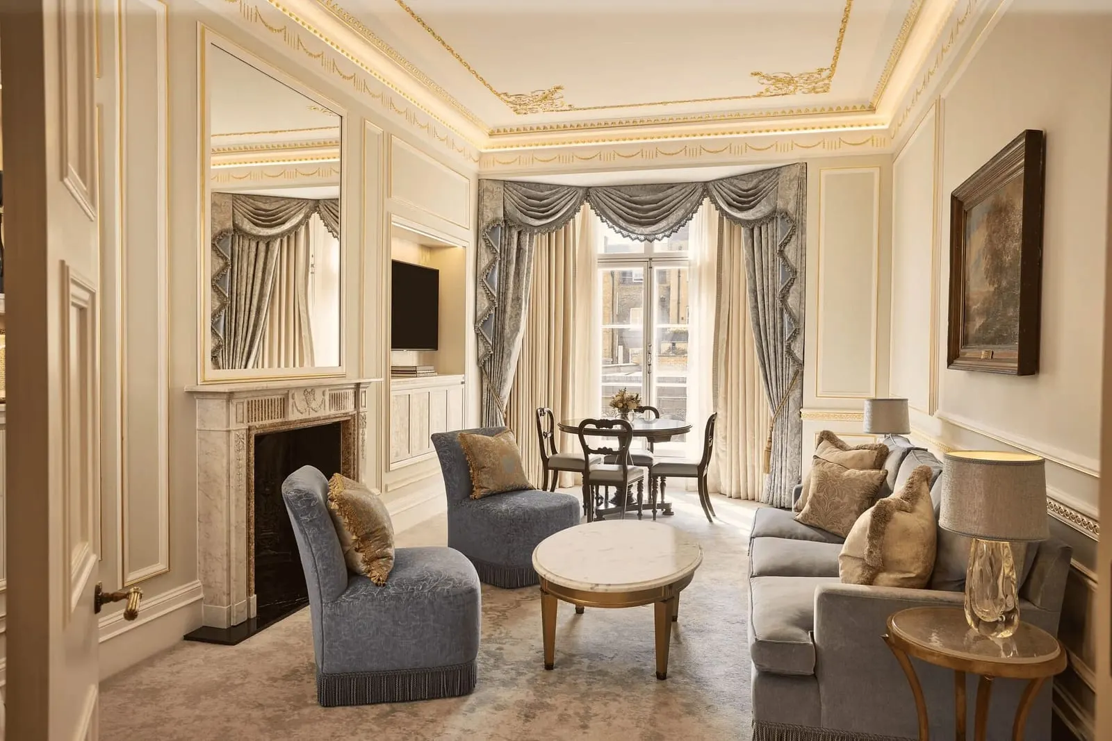 Two Bedroom Mayfair Suite at Claridge's: the living room with a marble fireplace, blue chairs and a small dining table