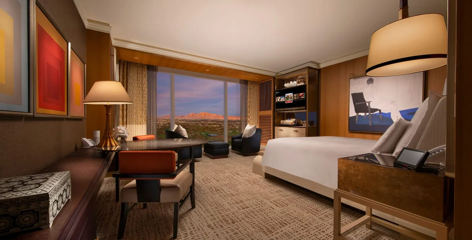 Wynn Resort King at Wynn Las Vegas: a king bed, a round marble-topped table with two orange-backed chairs, and two dark armchairs and a footstool by a floor-to-ceiling window