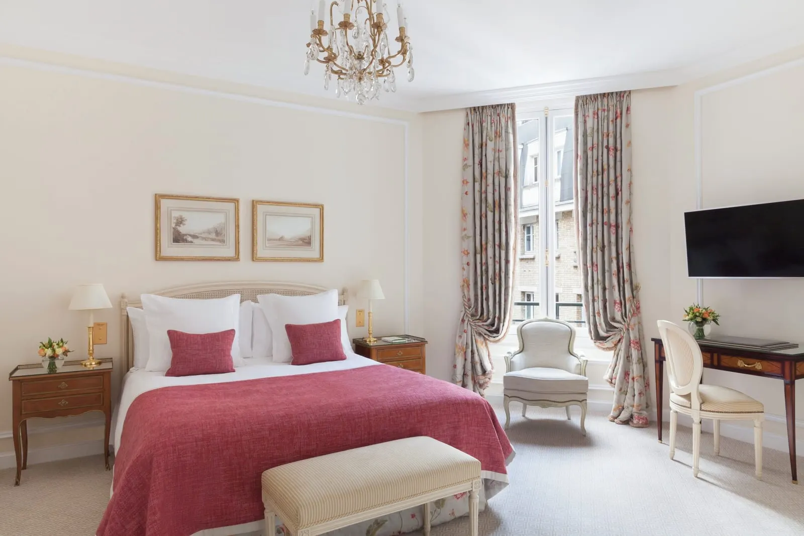 Superior Room at Le Bristol Paris: a double bed with a raspberry throw under two framed prints, an armchair by the tall window, a writing desk and a wall-mounted television