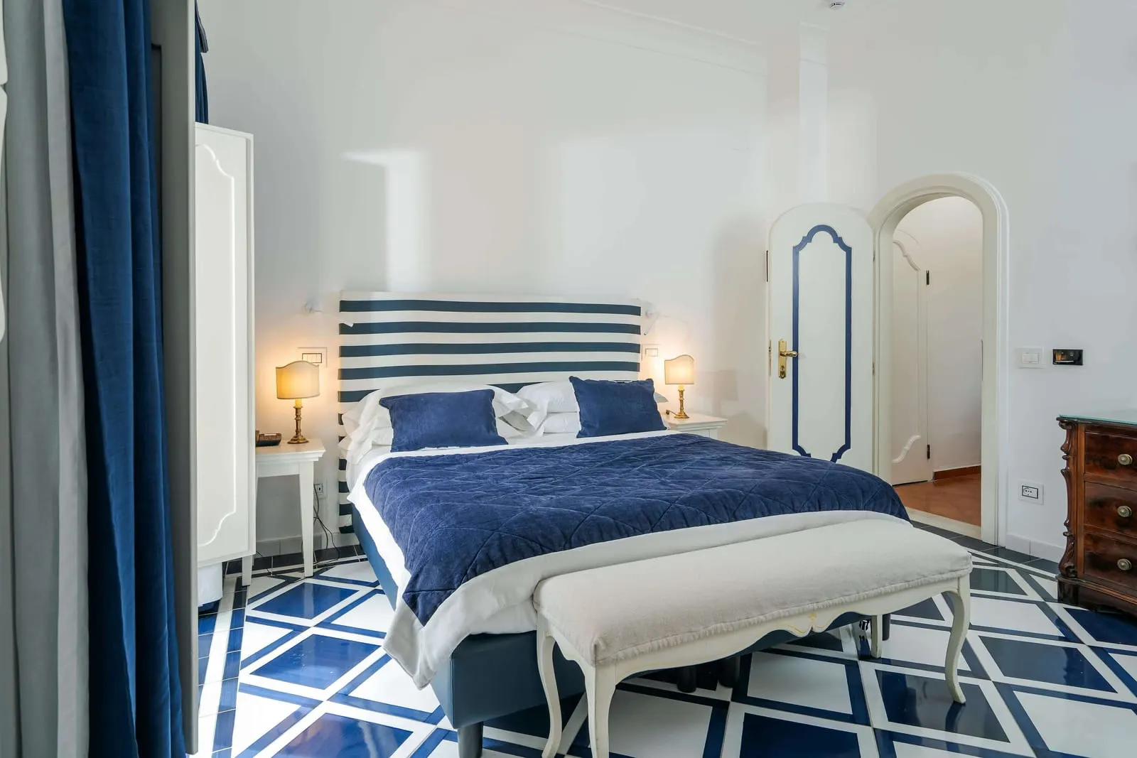 Standard Double Room im Palazzo Murat: ein Doppelbett mit blau-weiß gestreiftem Kopfteil auf einem blau-weiß gefliesten Boden