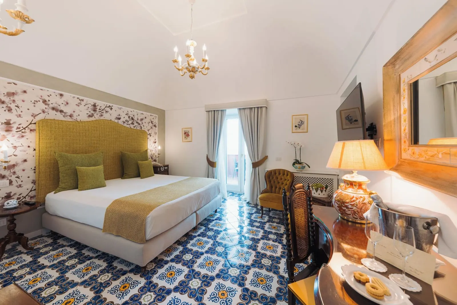 Executive Suite IBISCO at Palazzo Pascal: a double bed with a green headboard and a chandelier, beside a desk and an armchair