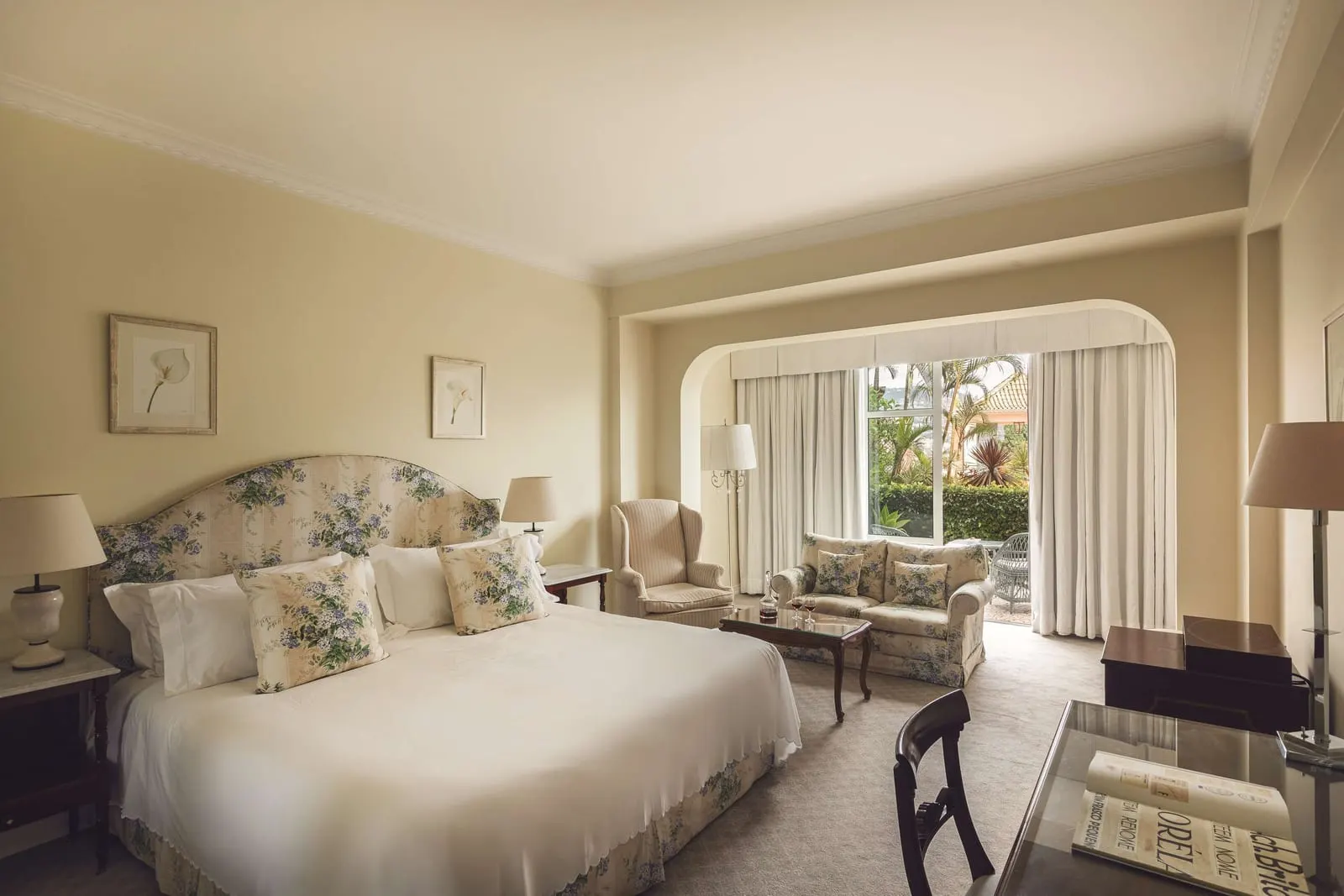 Family Room at Reid's Palace, A Belmond Hotel: a large bed and a sitting area with a sofa by glass doors onto the garden