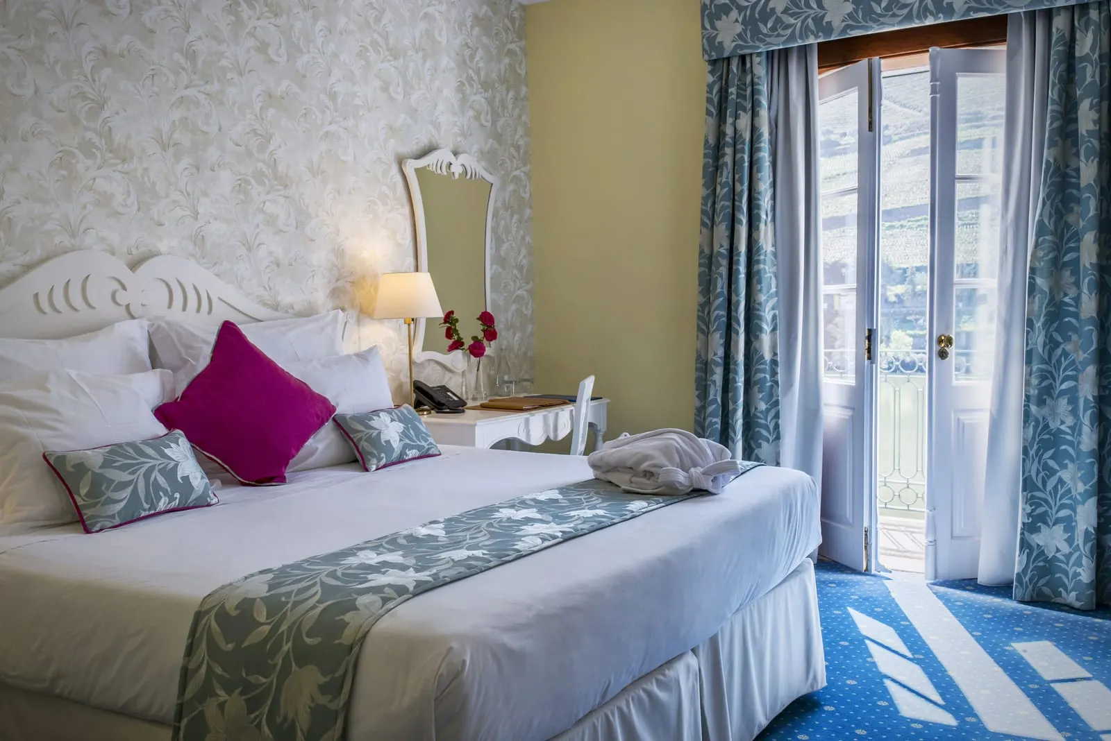 Junior Suite Douro River View at The Vintage House: the bed with a carved headboard and glass doors open to a balcony