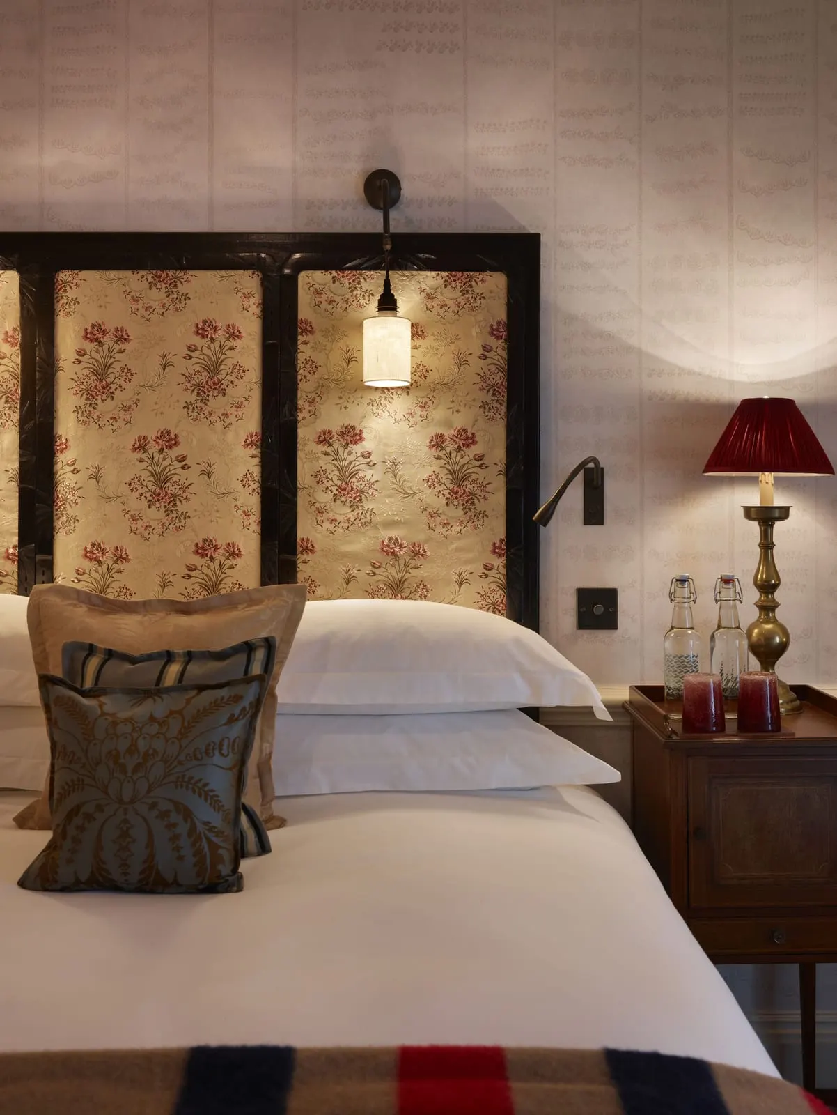 Deluxe King at The Zetter Marylebone: the headboard with floral fabric panels, a wall light and a red lamp