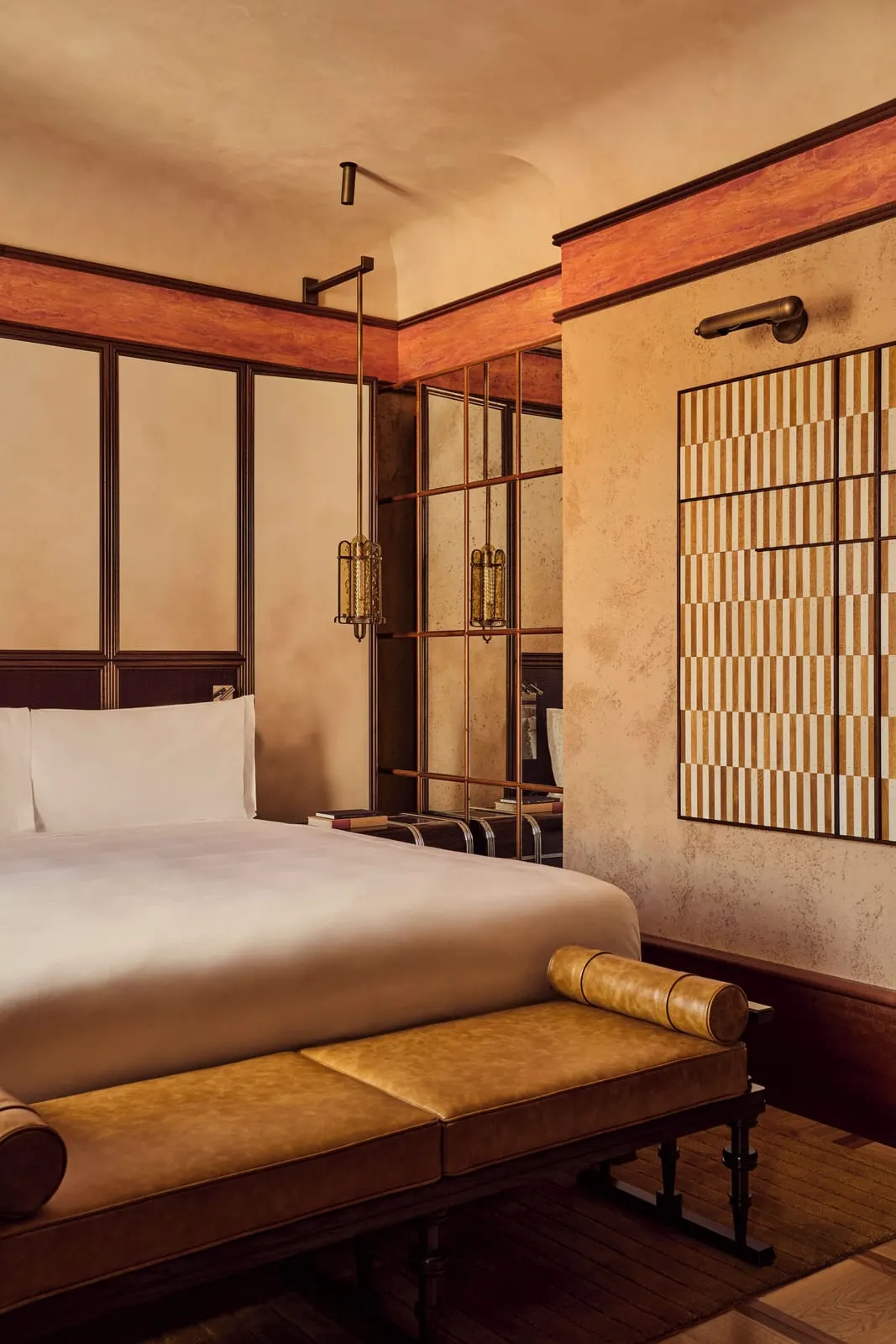 Junior Suite with Terrace at Orient Express La Minerva: the bed with a leather bench at its foot, a mirrored grid wall and lanterns