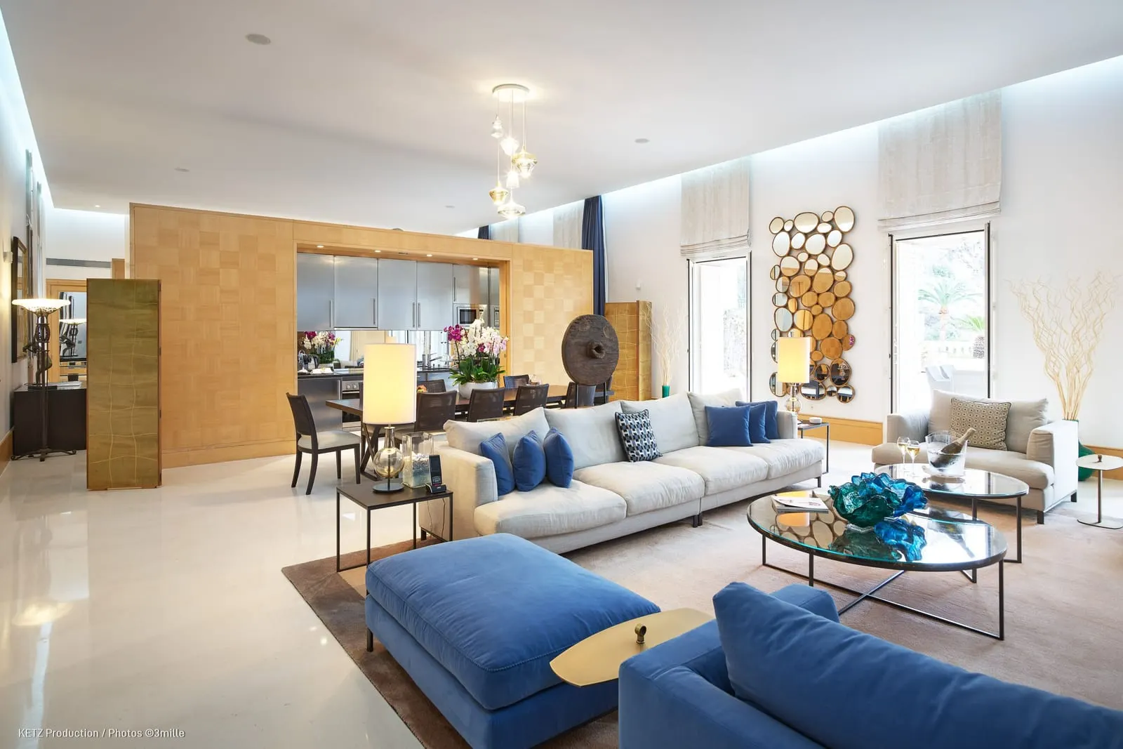 Executive Suite 210 at Cap Estel: the open-plan lounge with blue sofas, a dining table and the kitchen behind